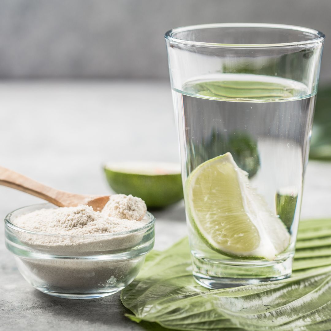 Glass of water with lime standing next to collagen powder